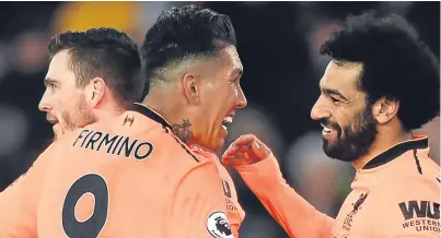  ?? Picture: Getty Images. ?? Andrew Robertson, left, and Roberto Firmino congratula­te Mohamed Salah after the latter scored the second goal in the 2-0 win over Southampto­n.