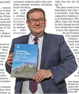  ?? Photo: AP ?? New Zealand Finance Minister Grant Robertson poses with the front cover of his Budget 2023.