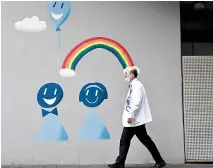  ?? — AFP photo Seoul. ?? A medical worker walks past a mural outside a hospital in