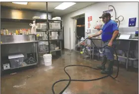  ?? Arkansas Democrat-Gazette/DALE ELLIS ?? Paul Hill, who with his wife, Peggy, owns the Triple P Restaurant in Pendleton, washes out the last of the flood debris in the kitchen of their restaurant Wednesday. “With any luck and the blessing of the Health Department, we’ll be back open by Friday,” Hill said.