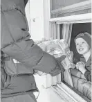  ?? Sarah Rice / Getty Images ?? Jake McSigue, 6, receives a package of bottled water through the window of his grandma’s Flint home in January.