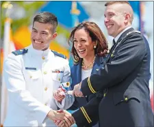  ?? ?? Above, Ensign Devin Gettman, his father, U.S. Army Lt. Col. Matthew Gettman, and Vice President Kamala Harris smile for a photo.
Left, the graduates toss their caps in the air as a flyby of Coast Guard helicopter­s passes overhead to conclude the ceremony.