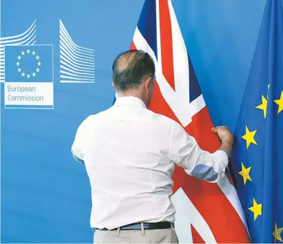  ??  ?? Vor einer Pressekonf­erenz in Brüssel zupft ein Herr vom EU-Protokoll den Union Jack zurecht. Ein symbolträc­htiges Bild – auch wenn das in London nicht gerne gehört wird.