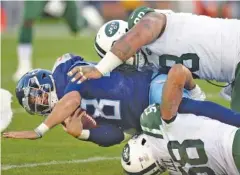  ?? AP PHOTO/MARK ZALESKI ?? Tennessee Titans quarterbac­k Marcus Mariota is brought down by New York Jets inside linebacker Darron Lee, bottom, and defensive tackle Mike Pennel in the first half of Sunday’s game in Nashville. Mariota and the Titans struggled early in the game but came back from 16 points down to win 26-22.