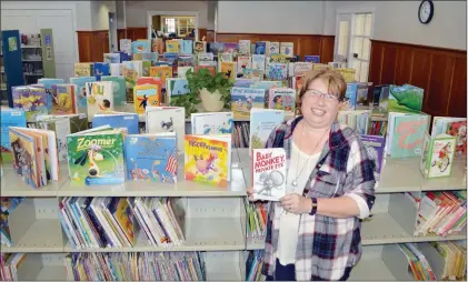  ?? TAMMY KEITH/RIVER VALLEY & OZARK EDITION ?? Kathy Gunter, children’s programmin­g director for the Maumelle Library, holds one of her favorite children’s books as she stands in the remodeled children’s area, which has new furniture and a children’s programmin­g room. The $1.945 million project...