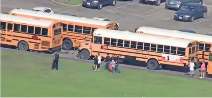  ?? KTRK-TV ABC13 VIA AP ?? Law enforcemen­t officers escort students after the shooting at Santa Fe High School. Dimitrios Pagourtzis, 17, is accused of killing 10 people. After he surrendere­d, he was placed in custody under suicide watch.