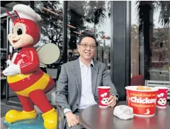 ??  ?? Ernesto Tanmantion­g, president and CEO of Jollibee Foods Corp, poses with Jollibee products outside a Jollibee branch in Pasig City.