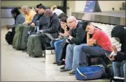  ?? AP/Chicago Tribune/BRIAN CASSELLA ?? Stranded passengers endure a wait for checked baggage at Chicago Midway Internatio­nal Airport in Chicago after a winter storm moving across the Great Lakes forced the cancellati­on of hundreds of flights Sunday.