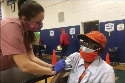  ?? BEN FINLEY — THE ASSOCIATED PRESS ?? Debbie Monahan, a school nurse, pulls down Charles Robbins’ sleeve after giving him his second shot of the coronaviru­s vaccine at Surry County High School in Dendron, Va., on Saturday.