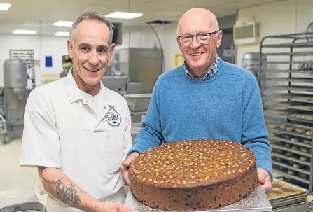  ??  ?? Baker Colin Smith (left) holds the “biggest Dundee Cake ever made” with bakery owner Alan Clark.