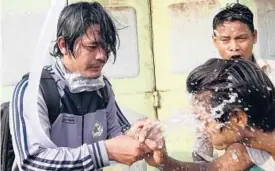  ?? AP ?? People rinse their faces after tear gas was used to disperse a protest Saturday in Mandalay, Myanmar. Security forces also used slingshots and rubber bullets against demonstrat­ors.