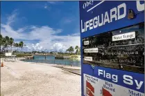  ?? RICHARD GRAULICH / THE PALM BEACH POST ?? A lifeguard sign warns visitors of closed water due to biological and respirator­y hazards at Dubois Park in Jupiter on Monday.