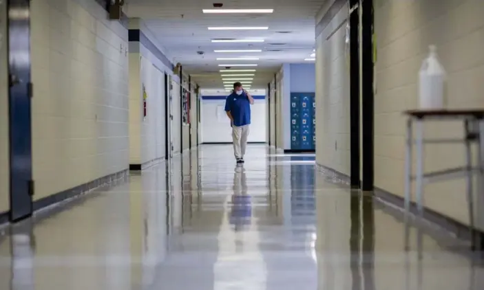  ?? Photograph: Stephen B Morton/AP ?? A middle school principal walks the empty halls of his school on 20 August 2021 in Wrightsvil­le, Georgia.