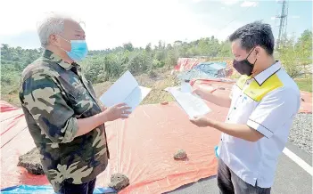  ??  ?? Bung Moktar (left) briefed on the process of repairing the stretch of Jalan Nangoh Paitan Kanibungan by Beluran Public Works Department engineer Kenny Paping.