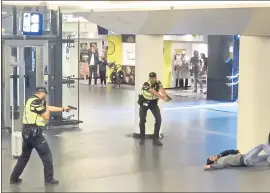  ?? THE ASSOCIATED PRESS ?? Dutch police officers point their guns at a wounded 19-year-old man who was shot by police Friday after a stabbing attack on two Americans in the Amsterdam train station.