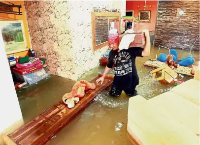  ??  ?? Water everywhere: Mohd Fauzi Mohd Lazim, 49, salvaging things in his inundated home in Kuantan.