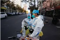  ?? — reuters ?? Pandemic prevention workers in protective suits stand on a street as outbreaks of Covid-19 continue in Beijing on Monday.