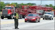  ?? NWA Democrat-Gazette/ANDY SHUPE ?? Lt. Josh McConnell with the Washington County Sheriff’s Office directs traffic Thursday while crews moving a transforme­r for Southweste­rn Electric Power Company add axles beneath the device before taking it across the Illinois River bridge on U.S. 62...