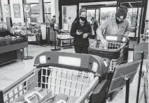  ?? ZBIGNIEW BZDAK TNS ?? Sarah and Robert Maxwell of Naperville use Dash Carts as they shop at the first Amazon Fresh grocery store in Naperville, Illinois, on Dec. 10, 2020. The high-tech Dash Carts automatica­lly ring items up as they're selected and allow shoppers to skip the checkout line. Amazon intends to invest more than $150 billion over the next 15 years on artificial intelligen­ce data centers around the world.