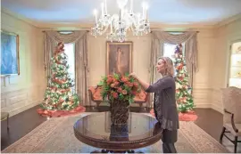  ?? CHUCK KENNEDY/THE WHITE HOUSE/STICHTING KUNSTBOEK VIA AP ?? Laura Dowling completes a holiday arrangemen­t of peach and coral roses in a magnolia leaf vase in the Vermeil Room in the White House.