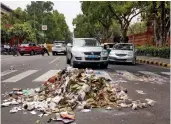  ?? — PTI, BUNNY SMITH ?? Police personnel gather as NDMC workers stage a demonstrat­ion to press for their various demands by piling garbage on Raisina Road in New Delhi on Thursday. A road just outside Parliament House is seen littered with garbage.