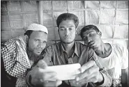  ?? AP/MANISH SWARUP ?? Mohammad Karim, 26, (center ) uses a mobile device to show other Rohingya Muslim refugees at a camp in Bangladesh a video reportedly showing mass graves at the Burmese village of Gu Dar Pyin.