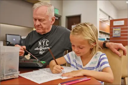  ?? Katharine Lotze/The
Signal ?? Dan Murphy colors Pokemon pictures with his granddaugh­ter Avery Smith while escaping the heat at the Newhall library on Wednesday.