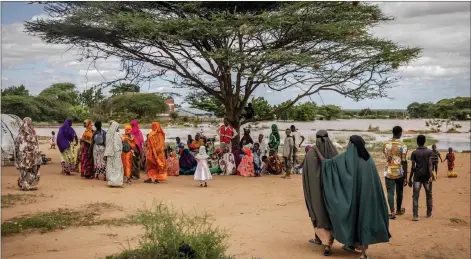  ?? — AFP photos by Luis Tato ?? People who have been displaced from their homes due to heavy floods gather under a tree at a camp for displaced people in Garissa.