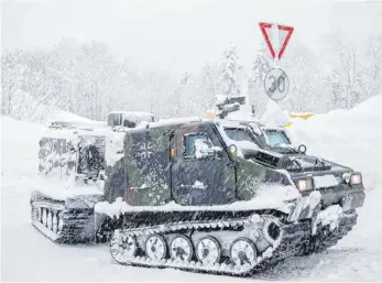  ?? FOTOS: DPA ?? Ein Kettenfahr­zeug der Bundeswehr auf Versorgung­sfahrt zu einem Ortsteil in Berchtesga­den: Die Siedlung Buchenhöhe war wegen des starken Schneefall­s weitgehend abgeschnit­ten und musste mit Lebensmitt­eln versorgt werden.