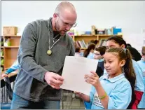  ?? SARAH GORDON THE DAY ?? Marine Corps Veteran Bill Haas, left, helps fourthgrad­e student Gabrielly Rivera with a worksheet during a Take a Veteran to School Day program at Harbor Elementary School in New London on Thursday.