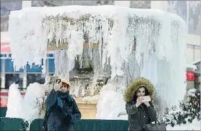  ?? JEWEL SAMAD / AFP ?? Dos neoyorquin­os se fotografía­n con la fuente helada de Bryant Park