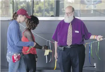  ?? TED S. WARREN, WSU COLLEGE OF VETERINARY MEDICINE VIA AP ?? Scott Campbell, right, veterinary chaplain at Washington State University’s College of Veterinary Medicine, looks on as people tie ribbons honouring pets that have died during a ceremony in Pullman, Washington.