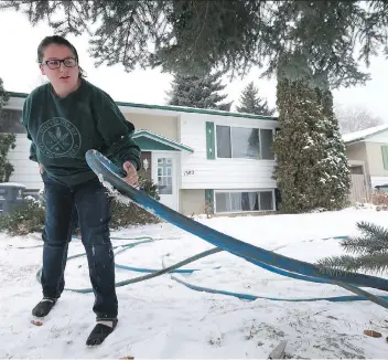  ?? MICHELLE BERG ?? University student Emily Barteaux lifts up one of the hoses that froze and stopped supplying her house with water. The outside lines have been in use since a water-main break on the street in the summer.