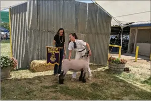  ??  ?? Maxine Naphan holds a sign Thursday that says “Supreme Champion” in reference to her daughter Joelle Naphan’s prize-winning ewe named Jury at the Butte County Fair in Gridley.