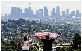  ?? CHRIS PIZZELLO / AP ?? A couple at Griffith Park in Los Angeles salute the United States Air Force Thunderbir­ds as they fly over downtown to honor frontline COVID-19 responders. The pandemic has revealed the blurred line between shared sacrifice and individual liberty.