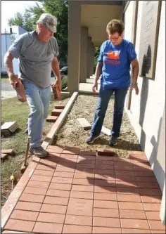  ?? The Sentinel-Record/Richard Rasmussen ?? DONORS’ NAMES: Billy Williams, left, and Karen Williams place pavers inscribed with donors’ names along a walkway at the Garland County Historical Society on Wednesday.