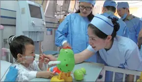  ?? HUANG ZHILING / CHINA DAILY ?? A nurse talks with a child of the Qiong ethnic group, who just had a surgical operation for congenital heart disease, at the Chengdu Military General Hospital.