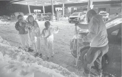  ?? RANDALL BENTON/AP ?? Jasmine DeGuzman, 12, left, and her sisters Rachael, 12, and Camille, 7, shiver as their father, Raymond DeGuzman, of Hayward, Calif., removes snow chains from his tires Dec. 28 in Camino, Calif. The DeGuzmans turned back as snow limited traffic to a crawl.