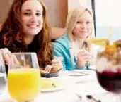  ??  ?? Journalist Laura Mitchell, right, was on a mission to see a grizzly bear while riding on the Rocky Mountainee­r. Here she enjoys breakfast aboard the train with fellow U.K. journalist Hollie-Rae Brader.