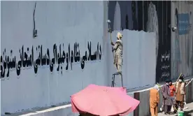  ?? Aamir Qureshi/AFP/Getty Images ?? A man paints over murals on a concrete wall in Kabul with a message reading ‘For an Islamic system and independen­ce, you have to go through tests and stay patient.’ Photograph: