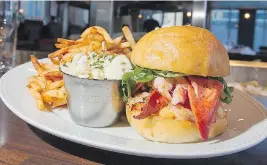  ??  ?? The lobster burger packs an impressive portion of lobster, spicy mayonnaise, arugula and a layer of melted cheddar cheese, with fries on the side.