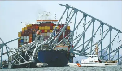  ?? AP photo ?? A Coast Guard cutter passes a cargo ship that is stuck under the part of the structure of the Francis Scott Key Bridge after the ship hit the bridge on Tuesday, in Baltimore, Md.