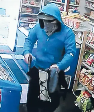  ??  ?? A CCTV still shows the robber holding a pistol inside the Coast Rd Dairy.