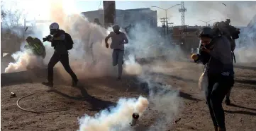  ?? — Reuters photo ?? Migrants from Central America and journalist­s are hit by tear gas after hundreds tried to illegally cross the Mexico border.