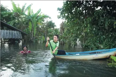  ?? TUWAEDANIY­A MERINGING / AFP ?? A man paddles a canoe over a flooded field at a village in Nakhon Si Thammarat, Thailand, on Monday.