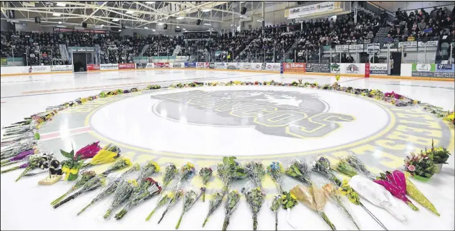  ?? JONATHAN HAYWARD/THE CANADIAN PRESS ?? Flowers lie at centre ice as people gather for a vigil at the Elgar Petersen Arena, home of the Humboldt Broncos, to honour the victims of a fatal bus accident in Humboldt, Sask., on Sunday, April 8.