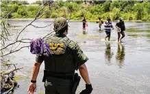  ?? Eric Gay/associated Press ?? A Border Patrol agent watches as a group of migrants walk across the Rio Grande on their way to turn themselves in.