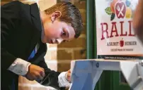  ??  ?? Nine-year-old James Nettles drops coins into a wishing well, part of Christ Church Cathedral’s efforts to raise money for a “Rally Against Hunger” event.