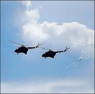  ?? AP/ SERGEI GRITS ?? Two Belarusian military helicopter­s fl y Tuesday during military exercises near the Volka village southwest of Minsk, Belarus.