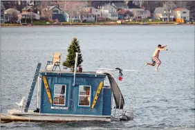  ?? BEN GARVER/THE BERKSHIRE EAGLE VIA AP ?? A man jumps into Pontoosuc Lake in Pittsfield, Mass., on Dec. 24, 2015. On Thursday the National Weather Service forecasted a warmer than normal 2018-19 winter for the northern and western three-quarters of the U.S.